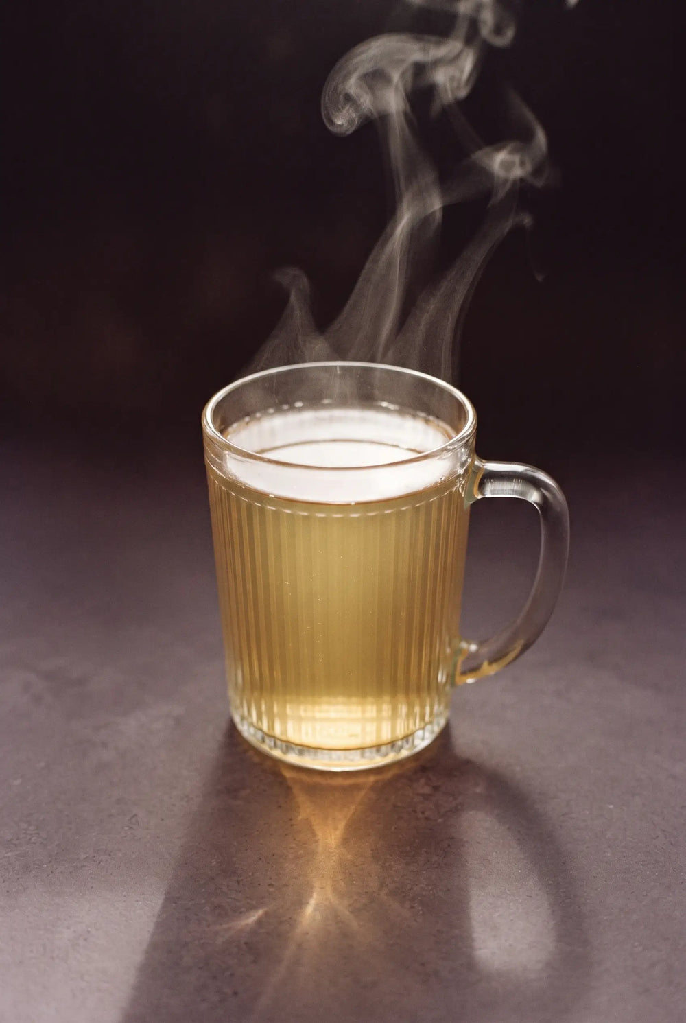 The Kinn Warmer: a glass mug of hot Kinn with steam rising