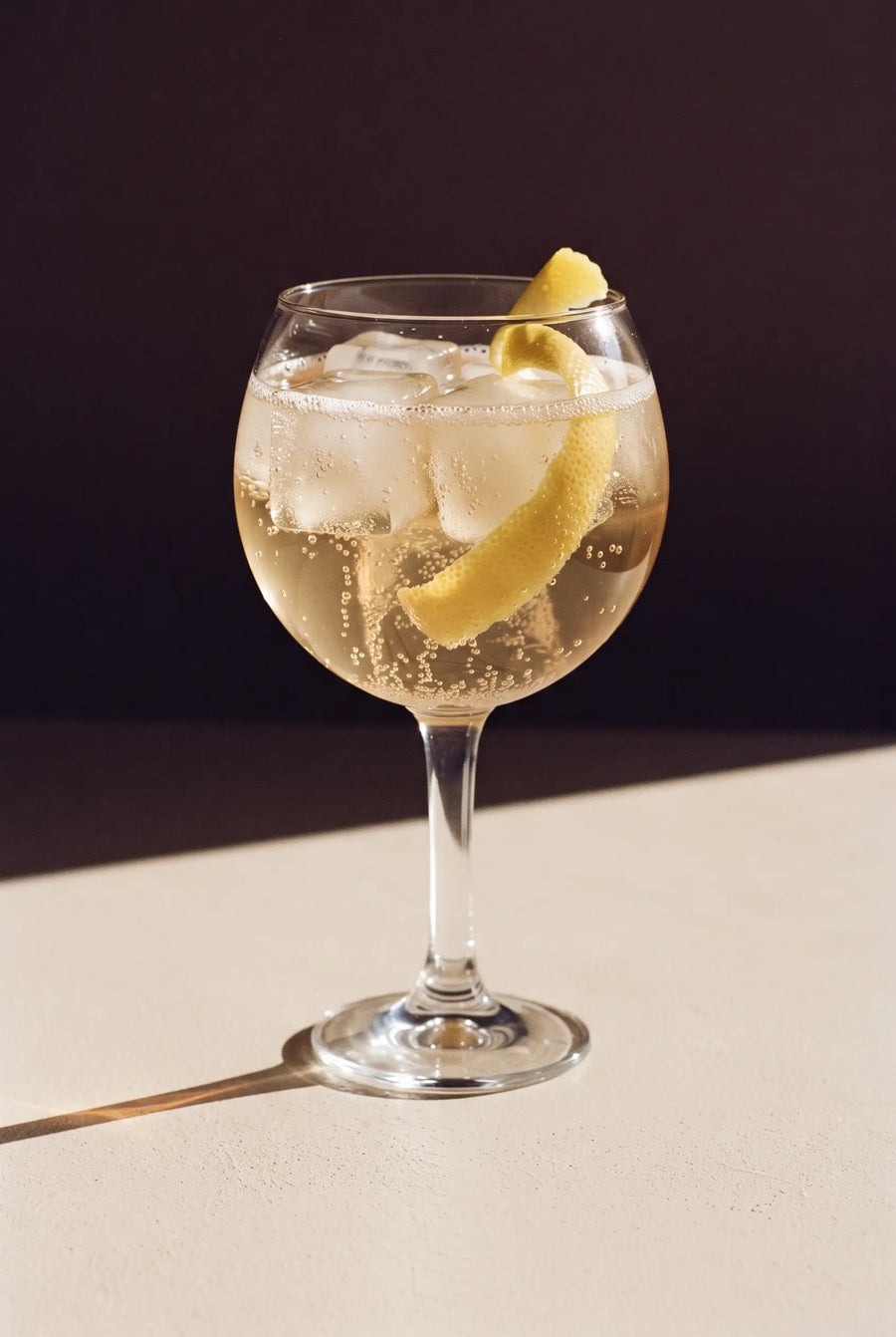 Kinn and Tonic: a stemmed copa glass of Kinn over ice with a curl of lemon peel