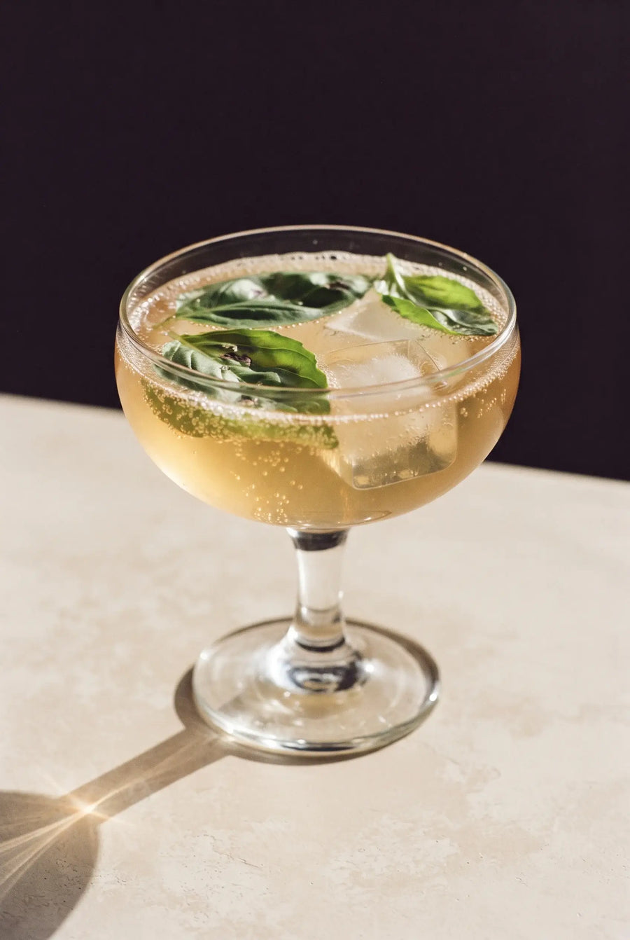 Kinn and Basil: a coupe of Kinn with basil leaves floating flat on the surface